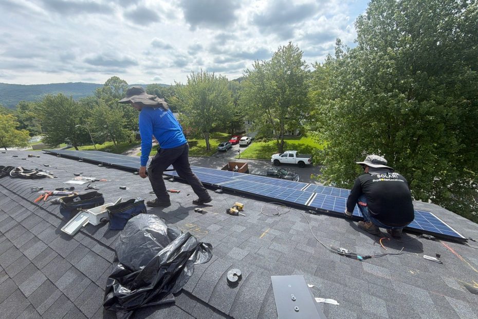 Roofing contractors working around solar panels on an asphalt shingle roof during roof repair